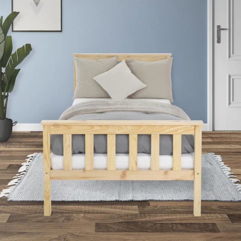 Ein einfaches Bett aus Holz mit grauer Bettwäsche und einem Kissen.