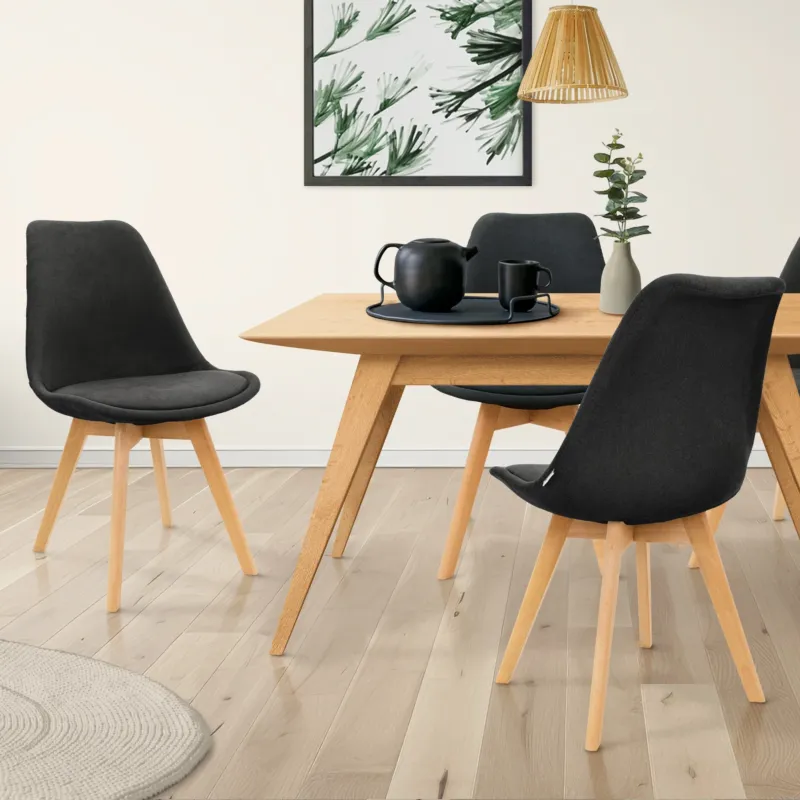 Ein Essbereich mit einem Holztisch, vier Stühlen und einer Pflanze im Hintergrund.