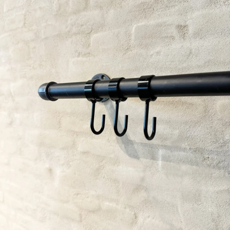 Schwarze O-Haken für Kleiderstangen - Set aus 5 Stück an schwarzer Kleiderstange vor beigefarbener Wand